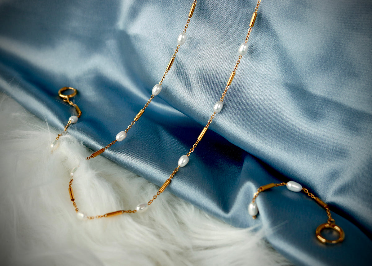 Pearl necklaces arranged on blue-gray fabric